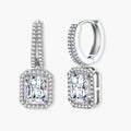 Sterling silver huggie hoops with emerald-cut moissanite drops featuring pavé-set crystals on white background.