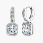 Sterling silver huggie hoops with emerald-cut moissanite drops featuring pavé-set crystals on white background.