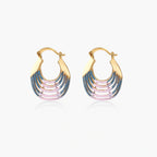 Gold hoop earrings with gradient blue-to-pink enamel in ribbed fan design on beige background