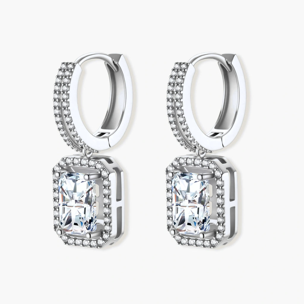 Sterling silver huggie hoops with emerald-cut moissanite drops featuring pavé-set crystals on white background.