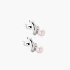 Rhodium-plated silver earrings with twisted X design and freshwater pearl drops on beige background