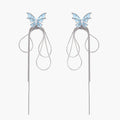 Long silver-tone earrings with powder blue enamel butterfly studs and flowing chain tassels on cream background