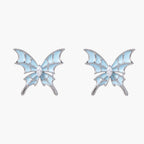 Long silver-tone earrings with powder blue enamel butterfly studs and flowing chain tassels on cream background