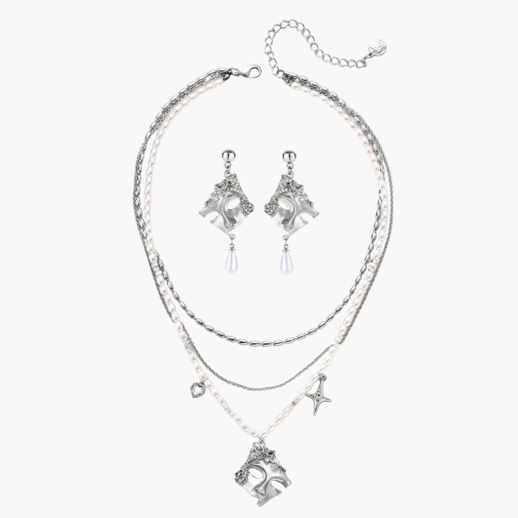 Ornate silver-toned masquerade mask jewelry set featuring rhinestone details and pearl drop earrings on white background.