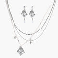 Ornate silver-toned masquerade mask jewelry set featuring rhinestone details and pearl drop earrings on white background.