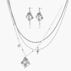 Ornate silver-toned masquerade mask jewelry set featuring rhinestone details and pearl drop earrings on white background.