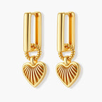 Gold-plated huggie earrings with textured heart charms featuring radiating sunburst patterns on white background.