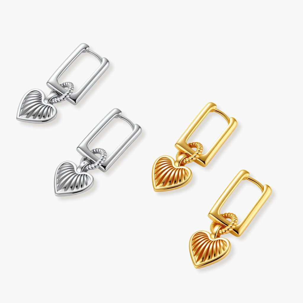 Gold-plated huggie earrings with textured heart charms featuring radiating sunburst patterns on white background.