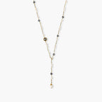 Y-shaped gold-plated necklace with white and gray freshwater pearls on cream background, showing adjustable drop design.