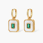 Gold-plated jewelry set with white enamel square pendants and emerald CZ stones on cream background.