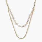 Layered gold chain necklace with organic baroque freshwater pearls and adjustable length on cream background